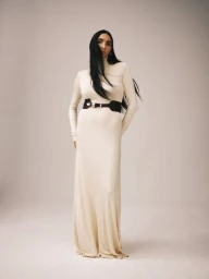 Model wearing a cream long-sleeve maxi dress and a dark wide belt against a neutral studio background.