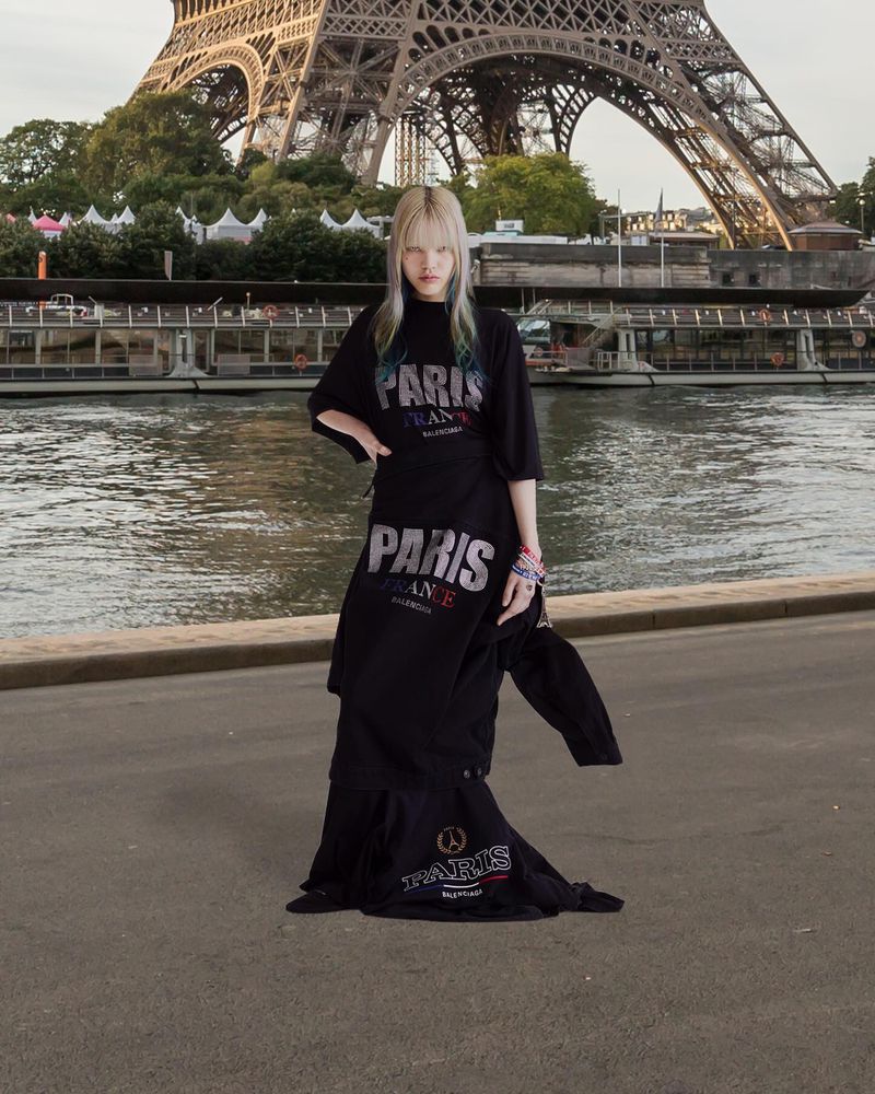 Woman wearing black Balenciaga t-shirt dress standing on an embankment with the Eiffel Tower in the background in Paris, France.