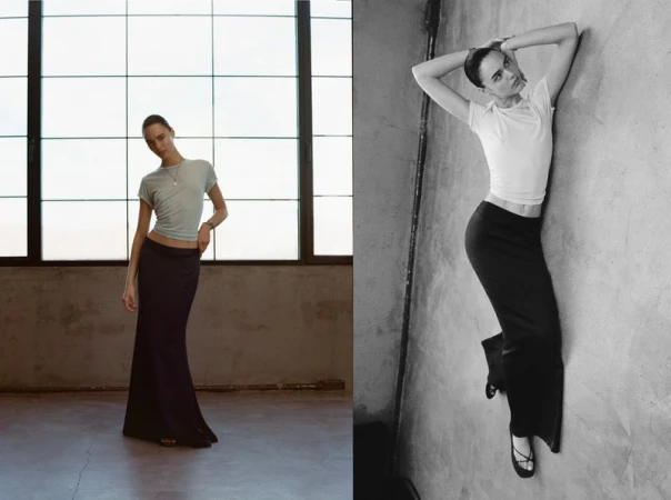 Fashion shot featuring a young adult female model posing in a light blue shirt and black skirt, standing in an indoor industrial space.