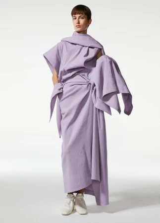 Model wearing a draped lilac Issey Miyake garment against a seamless white studio background