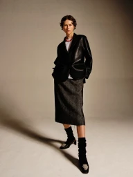 Model Bente Oort posing in a black blazer and grey midi skirt for the Rika Studios AW24 lookbook.