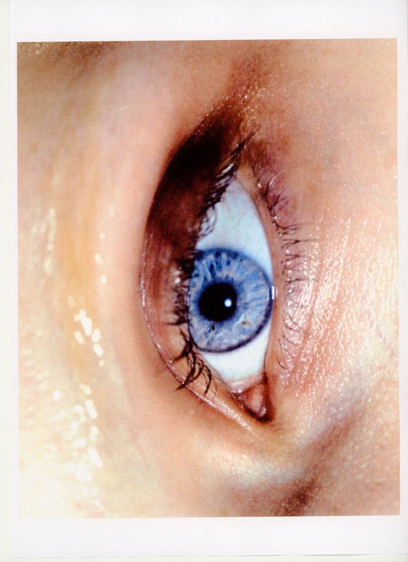 Close-up of a human eye with a blue iris, surrounded by skin and eyelashes, presented in a portrait-oriented composition.