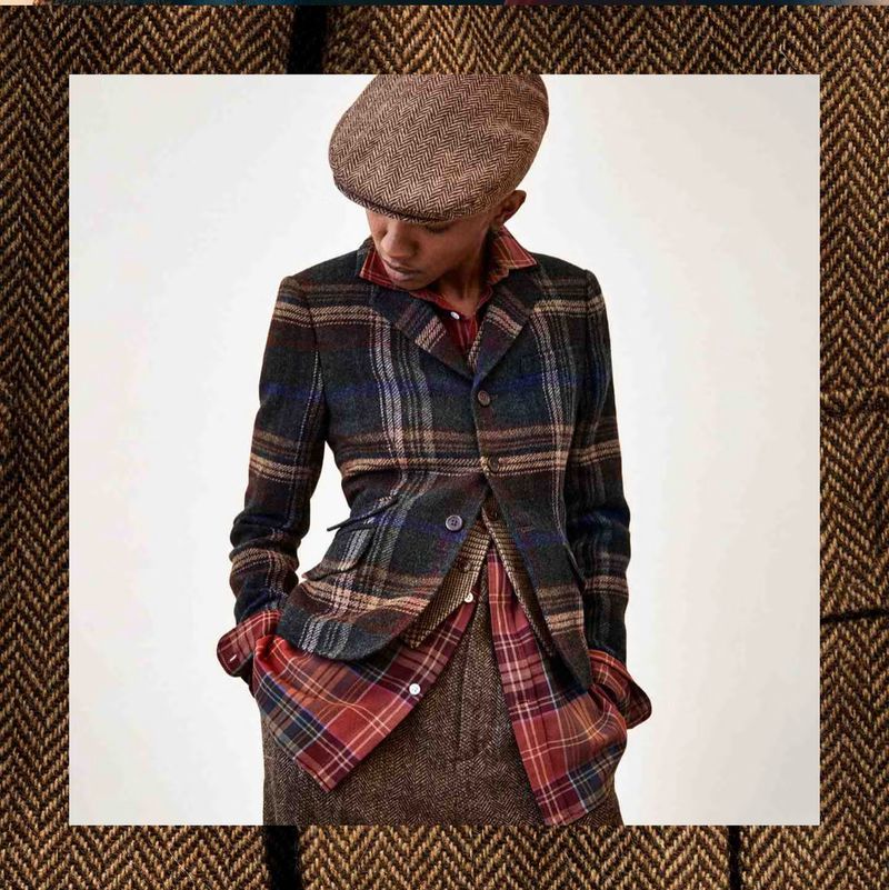 A woman poses in a stylish, patterned blazer and matching cap. The image is tightly framed to showcase the apparel and design details.