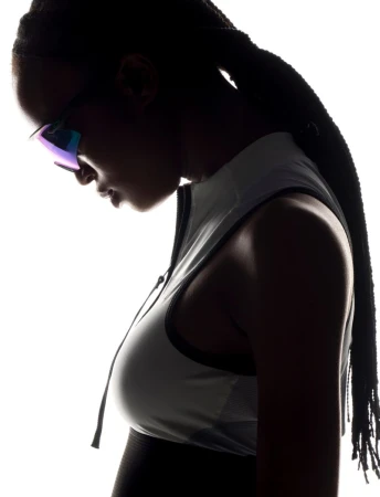 Silhouette portrait of a woman with braided hair wearing sport sunglasses and a sleeveless top against a bright white background.