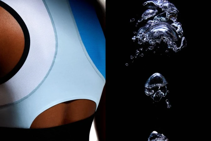Close-up shot showcases a light blue sports bra on a woman and water bubbles against a stark black background, with a focus on athletic wear.