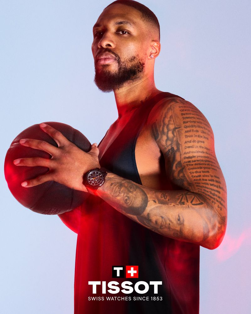 Athletic man with a beard holds basketball in studio, wearing a watch, showcasing sports, fitness, and beauty with Tissot logo.