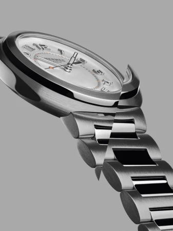 Wristwatch with a metal band and round silver face with numerical hour markers and silver hands is photographed in a close-up studio shot.