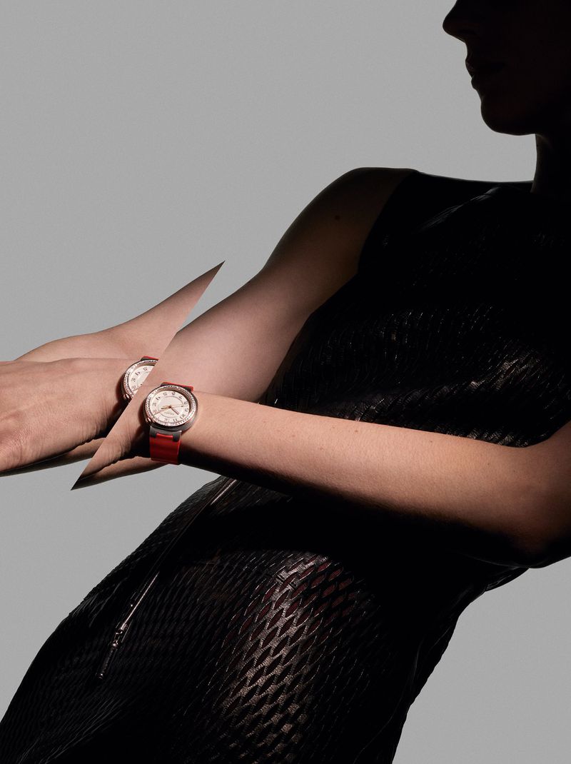 Close-up studio shot featuring two luxury wristwatches on the arms of a fashion model wearing a textured black dress against a grey backdrop.