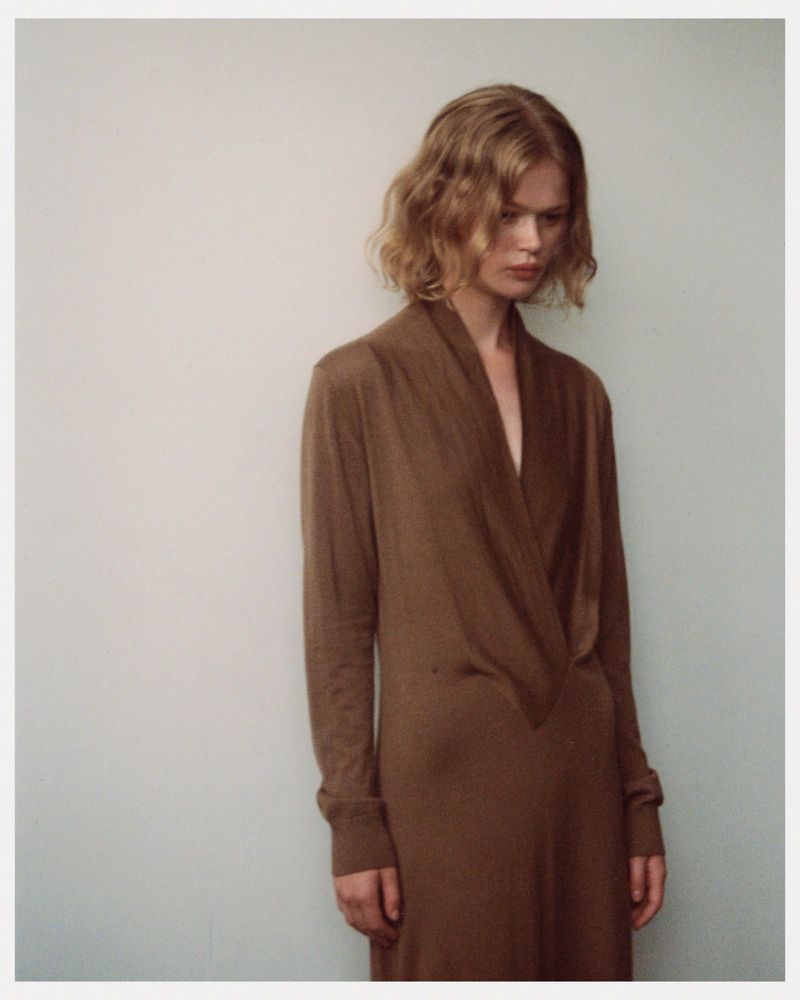 Model wearing a brown V-neck dress against a neutral grey wall for SEMICOUTURE 360