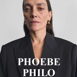 Model Laura Ponte in a structured black blazer and gold drop earrings facing the camera for Phoebe Philo.