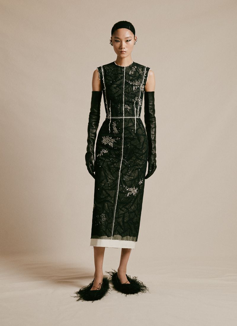 Elegant Asian model showcases black sequined dress with long gloves and feathered shoes in a studio fashion photoshoot.