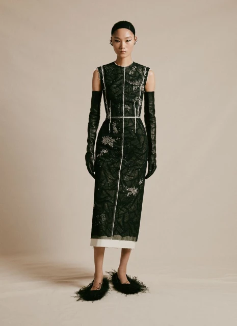 Elegant Asian model showcases black sequined dress with long gloves and feathered shoes in a studio fashion photoshoot.