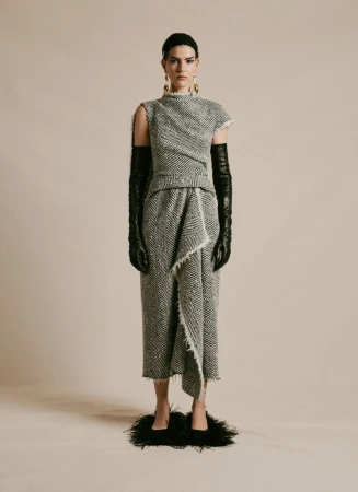Full-length shot of a woman in a textured gray dress with fringe, styled with opera gloves and black feather shoes, in a studio setting.