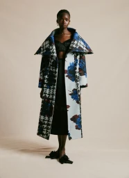 Model wearing an oversized wide-collar houndstooth and floral print coat for Erdem against a neutral studio backdrop.