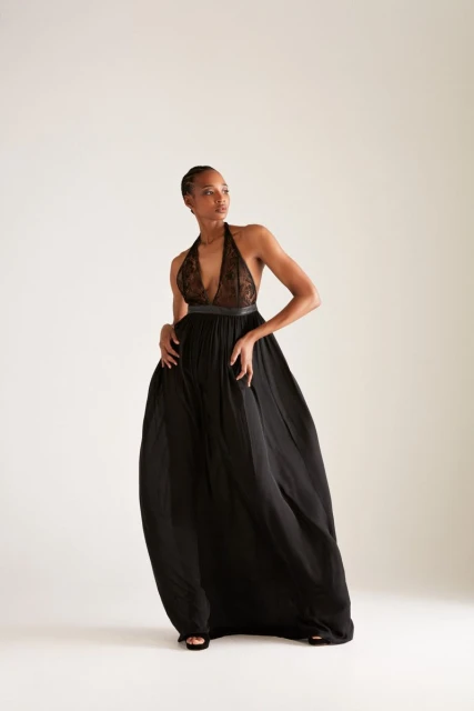 Elegant Black Woman in Flowing Halter Gown. Full-length shot, soft lighting. Fashion, beauty, and style concepts. Studio photography.