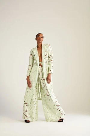 Fashionable adult woman poses in a light green patterned jacket and pants in a photo studio setting. Neutral backdrop and studio lighting.