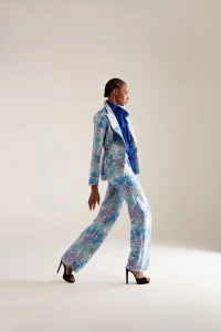 Model in blue floral patterned trouser suit and royal blue blouse walking against a neutral studio backdrop