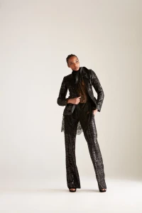 Model wearing a black sequined suit with a sheer blouse against a neutral studio background