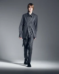 Herman Ingerstedt walks forward in a draped grey pinstripe suit against a neutral grey seamless studio backdrop.