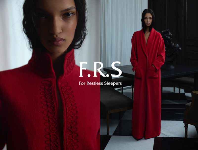 Fashion advertisement features a female model in a red robe, with a brand logo in the foreground, shot in an indoor setting.