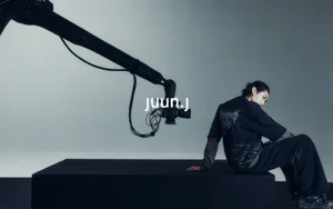 Model seated on a black platform next to a mechanical camera arm for Juun.J 24 summer online visual campaign.