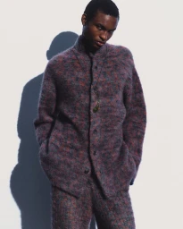 Model in textured patterned knit jacket against white seamless background