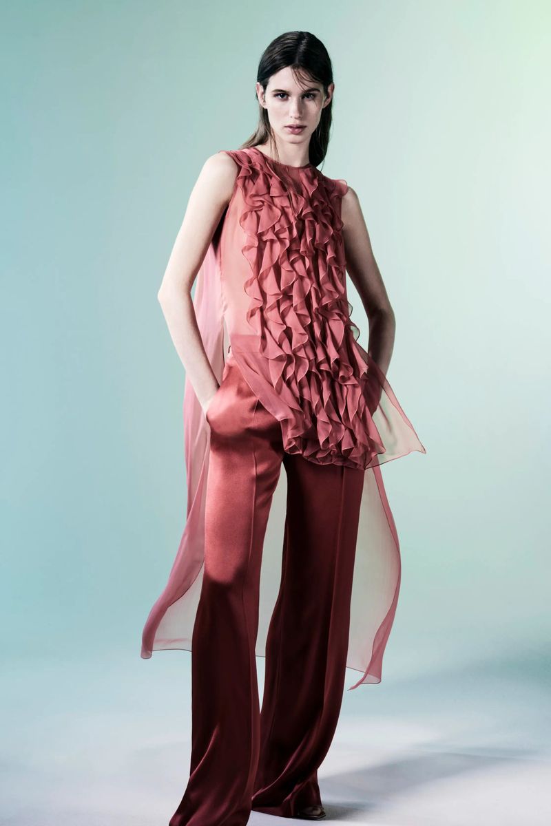 Fashion model wears a sleeveless ruffled top with palazzo pants in a studio shot, showcasing a modern, elegant, and stylish aesthetic.