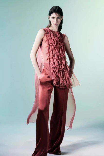 Fashion model wears a sleeveless ruffled top with palazzo pants in a studio shot, showcasing a modern, elegant, and stylish aesthetic.