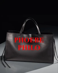 Black smooth leather structured tote bag with top handles on a shaded surface with red Phoebe Philo text overlay.
