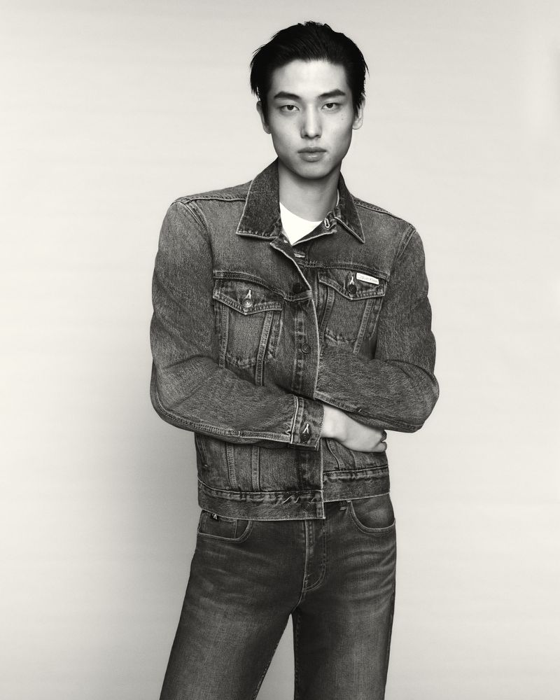 Model Cheng Qiang standing with arms crossed wearing a denim jacket and jeans against a neutral studio backdrop.
