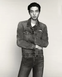 Model Cheng Qiang standing with arms crossed wearing a denim jacket and jeans against a neutral studio backdrop.