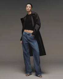 Model wearing blue denim jeans and dark jacket against a neutral grey background for Calvin Klein Denim Series project