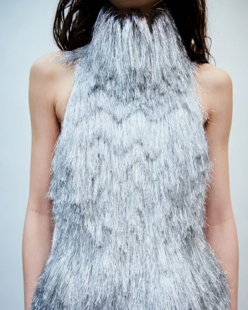 Model wearing a shimmering silver fringe halterneck top against a plain light background