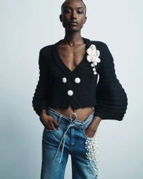 Model Amelie Nsengiyumva wearing a black cropped knit jacket and pearl-embellished denim jeans for Hellessy Resort 25.