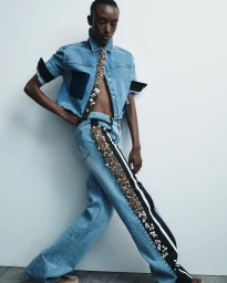 Model Amelie Nsengiyumva wears a sequin-trimmed denim top and wide-leg jeans against a white backdrop for Hellessy Resort 25.
