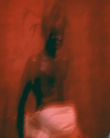 Blurry, dreamlike image featuring a figure against a red background; long exposure effects add an abstract feel.