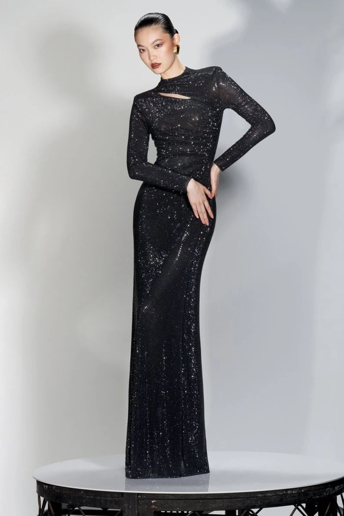 Model wearing a sparkly black evening dress with a keyhole cutout on a round platform against a plain grey backdrop.