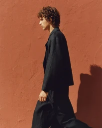 Profile shot of a male model in a dark shirt against a textured terracotta wall for Zara