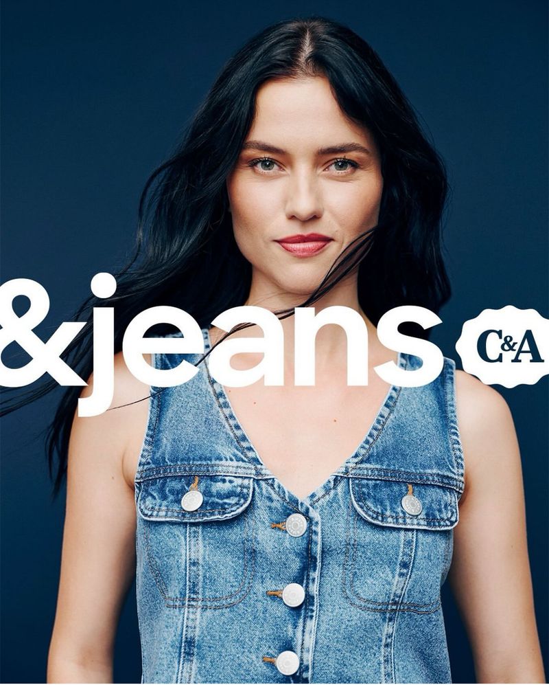 A woman in a denim top poses against a blue backdrop for a C&A jeans advertisement, her dark hair catching the light.