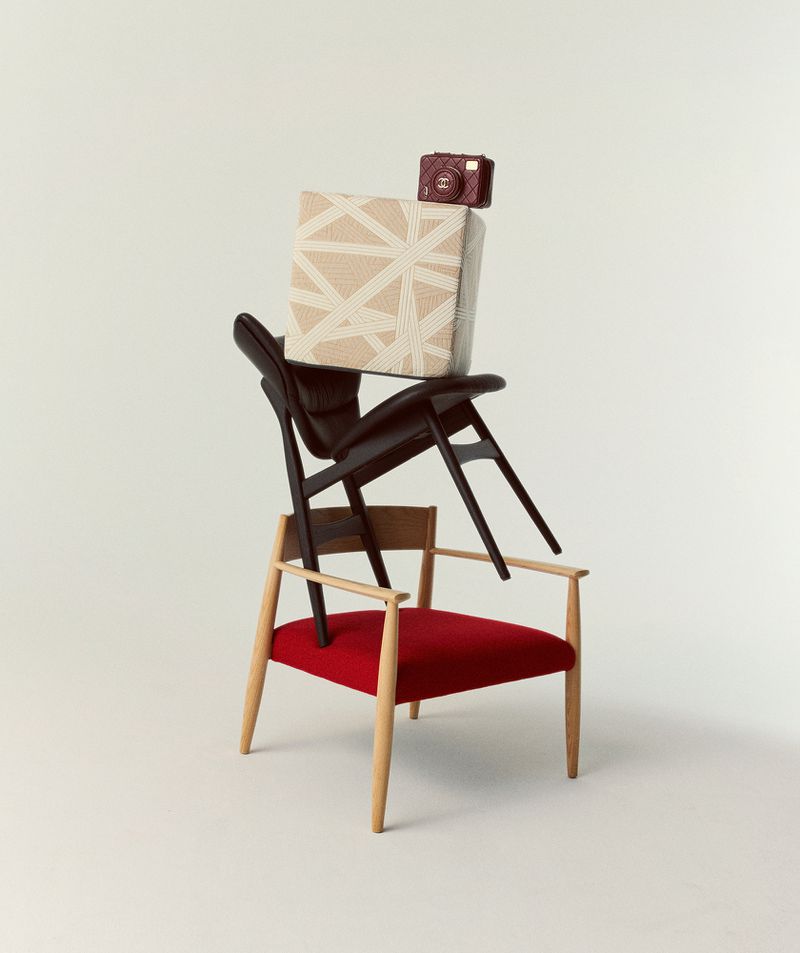 Stack of chairs and a camera against a white backdrop, creating an artistic and visually intriguing composition.