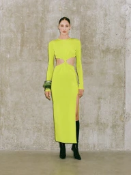 Model wearing a bright yellow cut-out long-sleeve dress and dark boots against a concrete wall