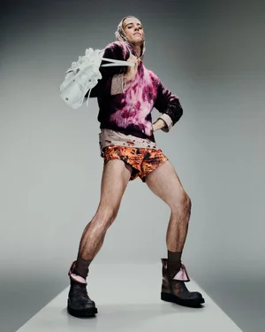Model Jordan Robson in pink patterned knit and orange shorts carrying a white bag for Acne Studios S/S 25 Mens Lookbook