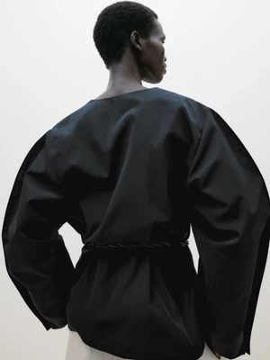 Model Amar Akway seen from behind wearing a black top with voluminous sleeves for Massimo Dutti