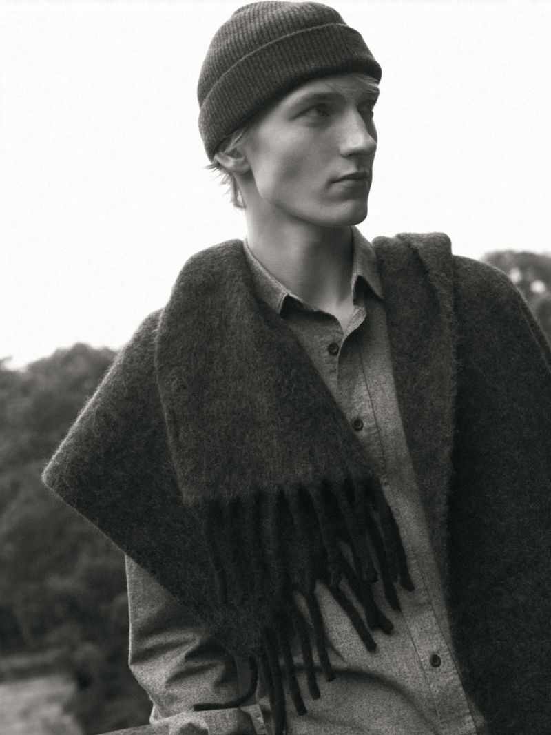 Monochrome portrait of Pierrick Gregoire wearing a beanie, shirt, and fringed scarf for Massimo Dutti