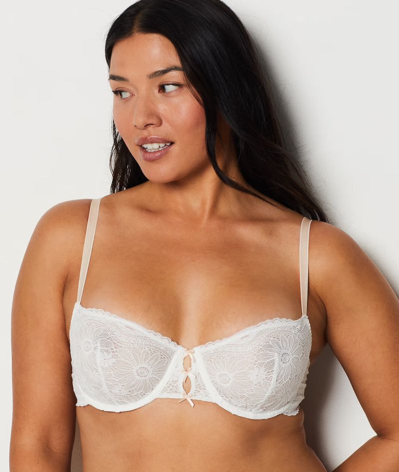 Portrait of an adult woman wearing a white lace bra against a light background, fashion and beauty concept, indoor studio shot.