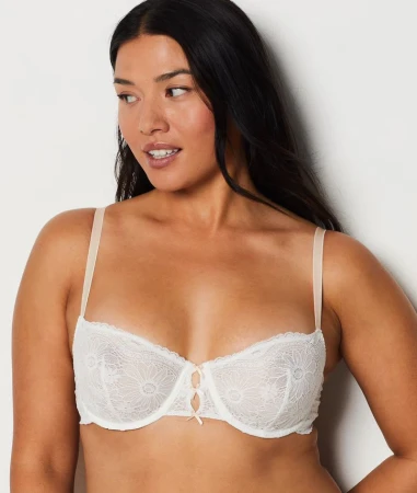Portrait of an adult woman wearing a white lace bra against a light background, fashion and beauty concept, indoor studio shot.