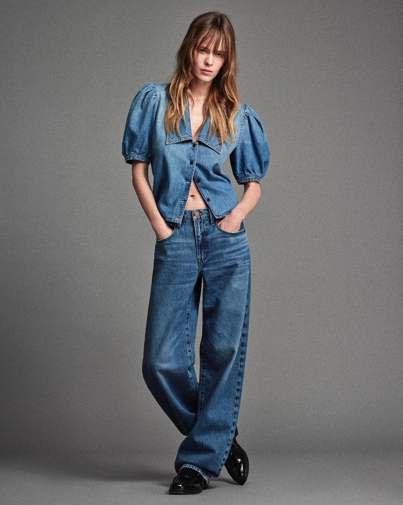 Model Kristine Lindseth in a puff-sleeve denim top and wide-leg blue jeans against a grey studio backdrop.