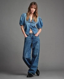 Model Kristine Lindseth in a puff-sleeve denim top and wide-leg blue jeans against a grey studio backdrop.