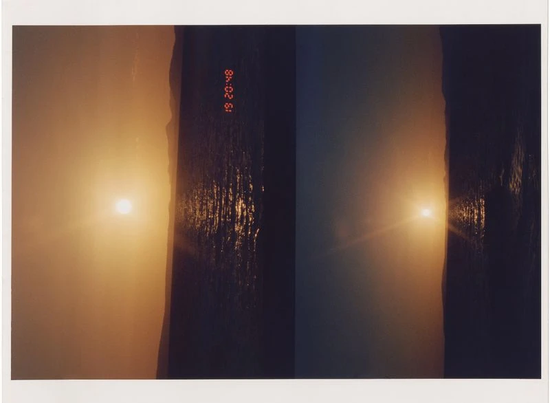 Scenic golden sunset view of the ocean with mountains in the distance reflecting light off the water and time stamp.