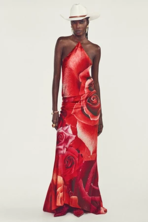 Model Arame Sall wearing a red rose print halter gown and white cowboy hat against a clean studio backdrop.